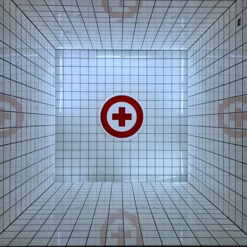 Croix médicale rouge au fond d’une salle carrelée de blanc